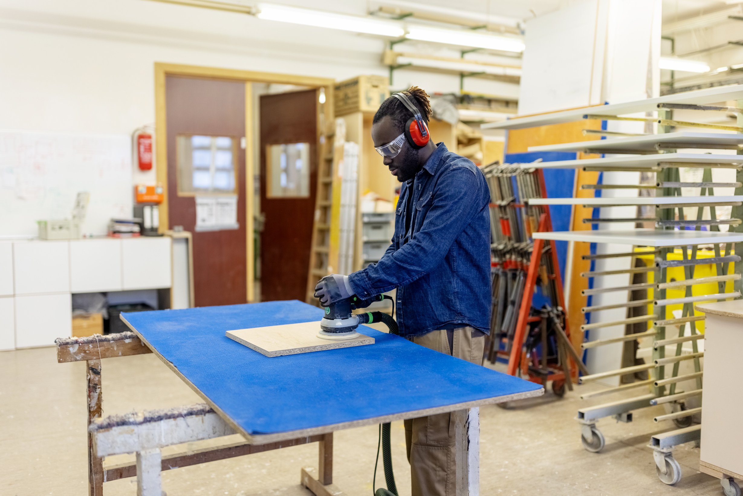 Carpenter sanding piece of wood with sanding machine at woodshop